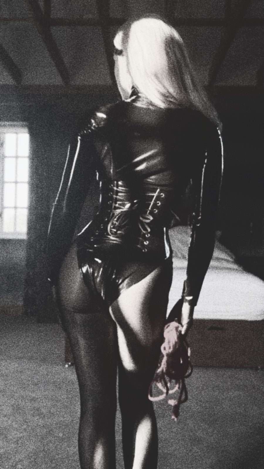 Aria from behind in black latex, a coil of rope in her hand.